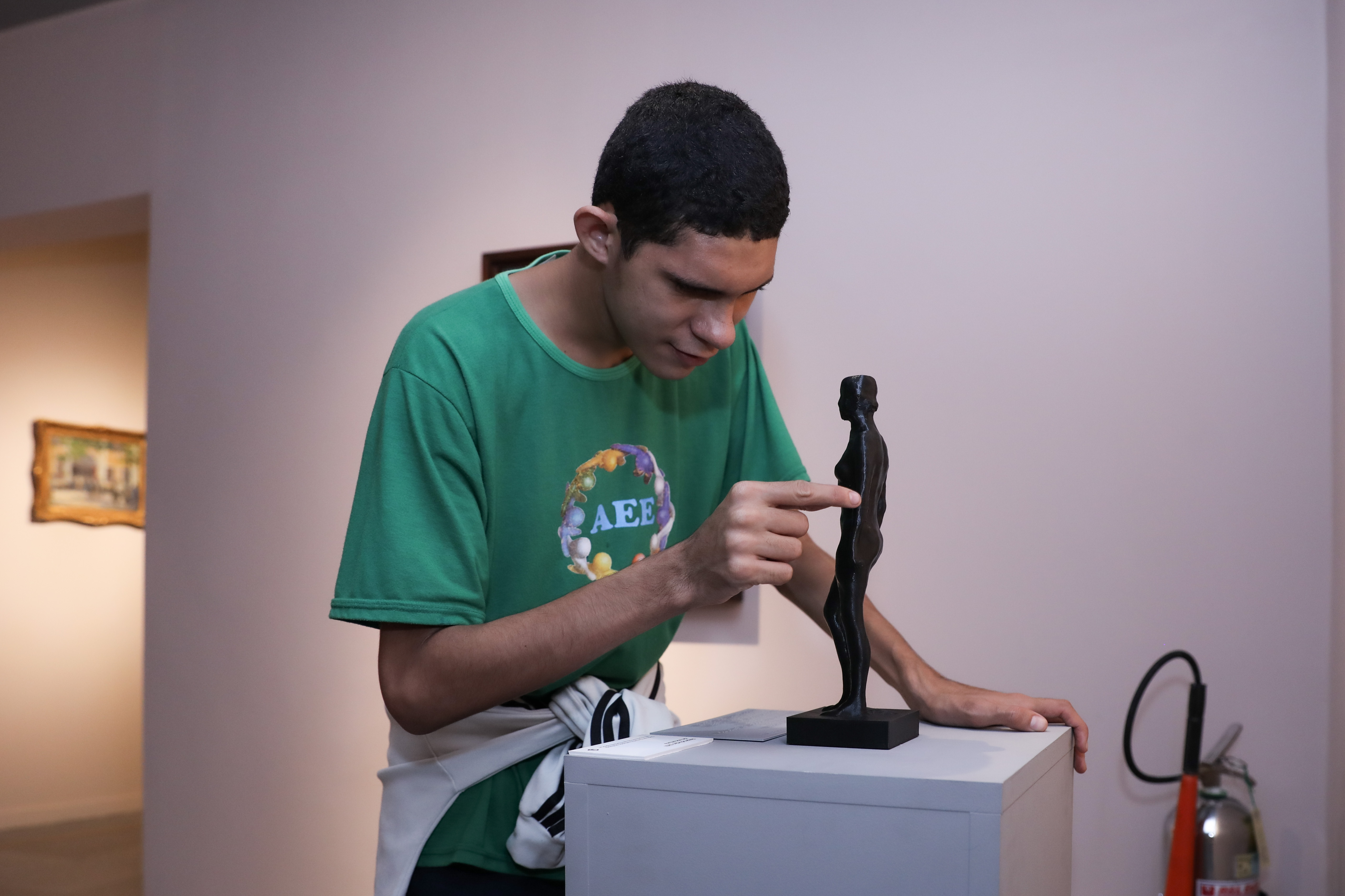 Estudante José Gabriel Sobreira dos Santos apreciando peça tátil da escultura 