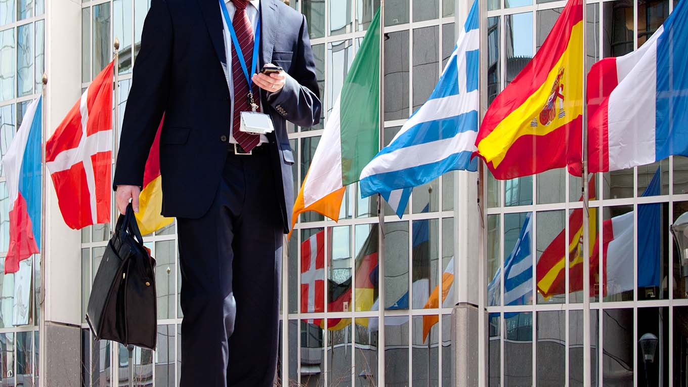 Um profissional caminha em frente a bandeiras de várias nacionalidades.