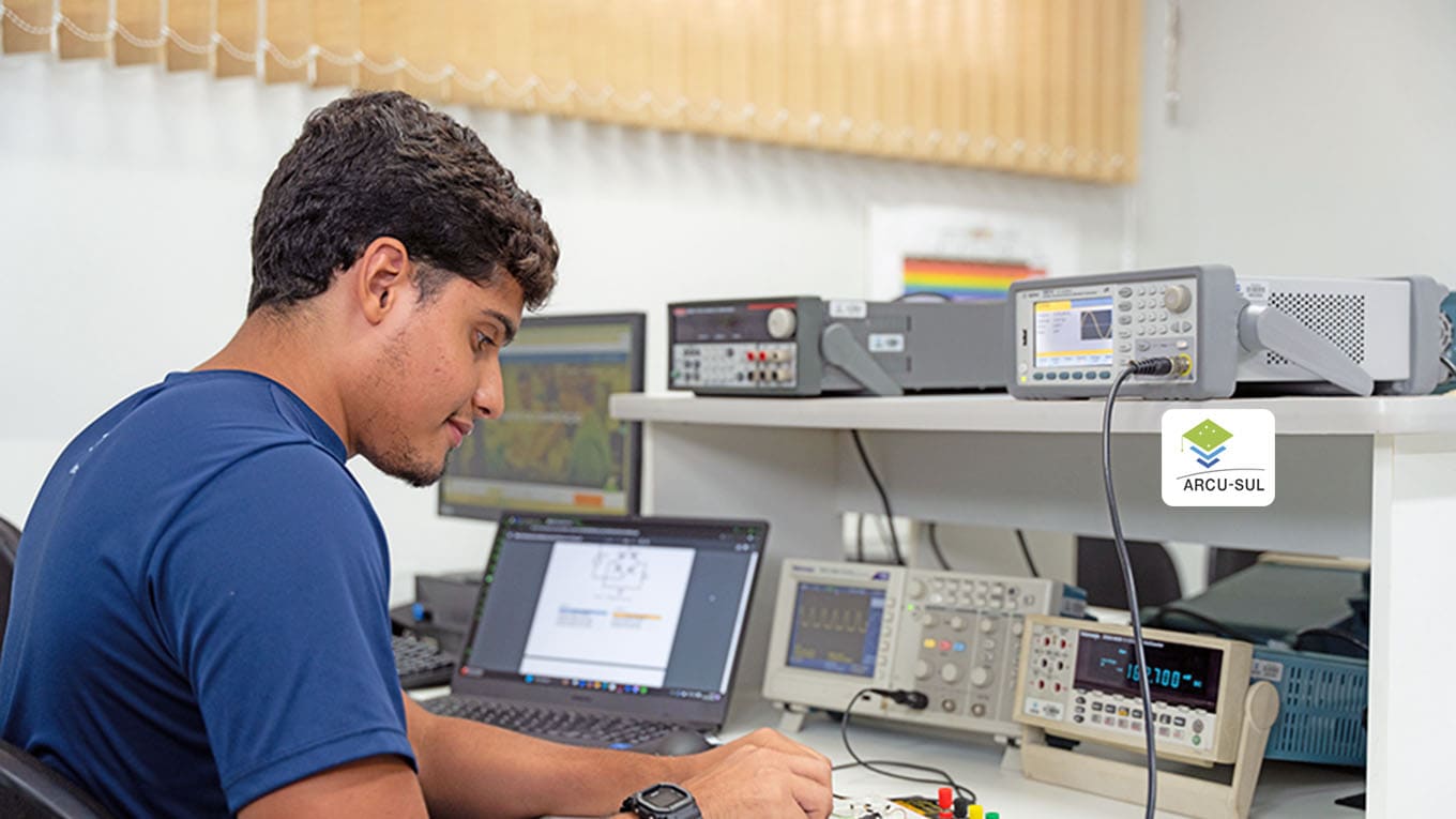 aluno manipula equipamento em meio a computadores