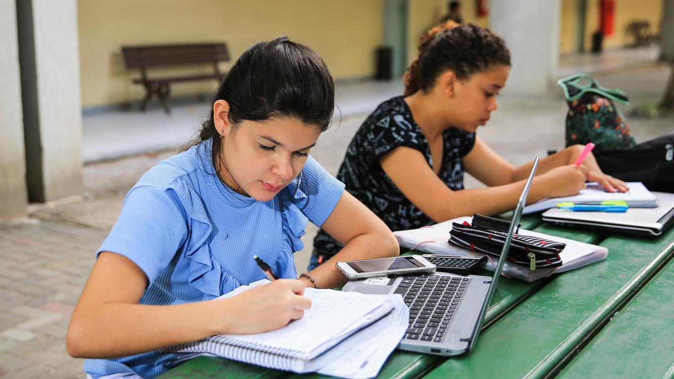 Uma estudante olha concentrada para a tela do computador.