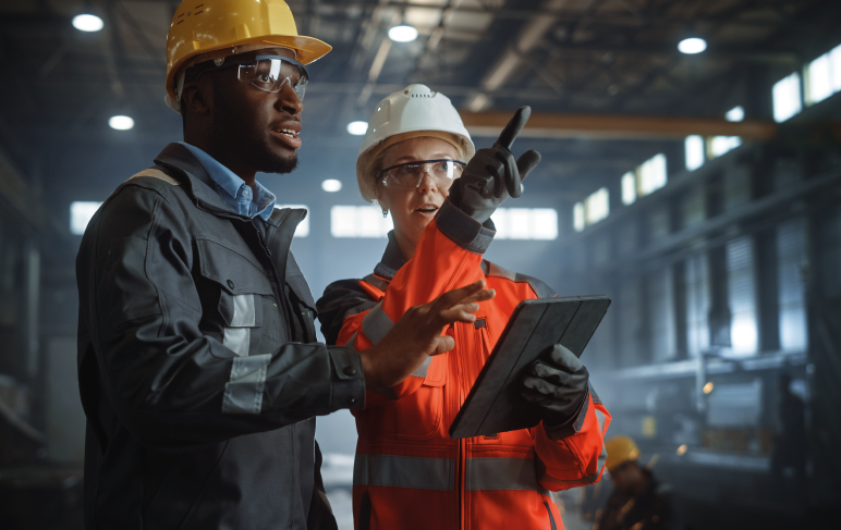 Dois engenheiros da indústria estão na fábrica de metal de aço usando tablet.