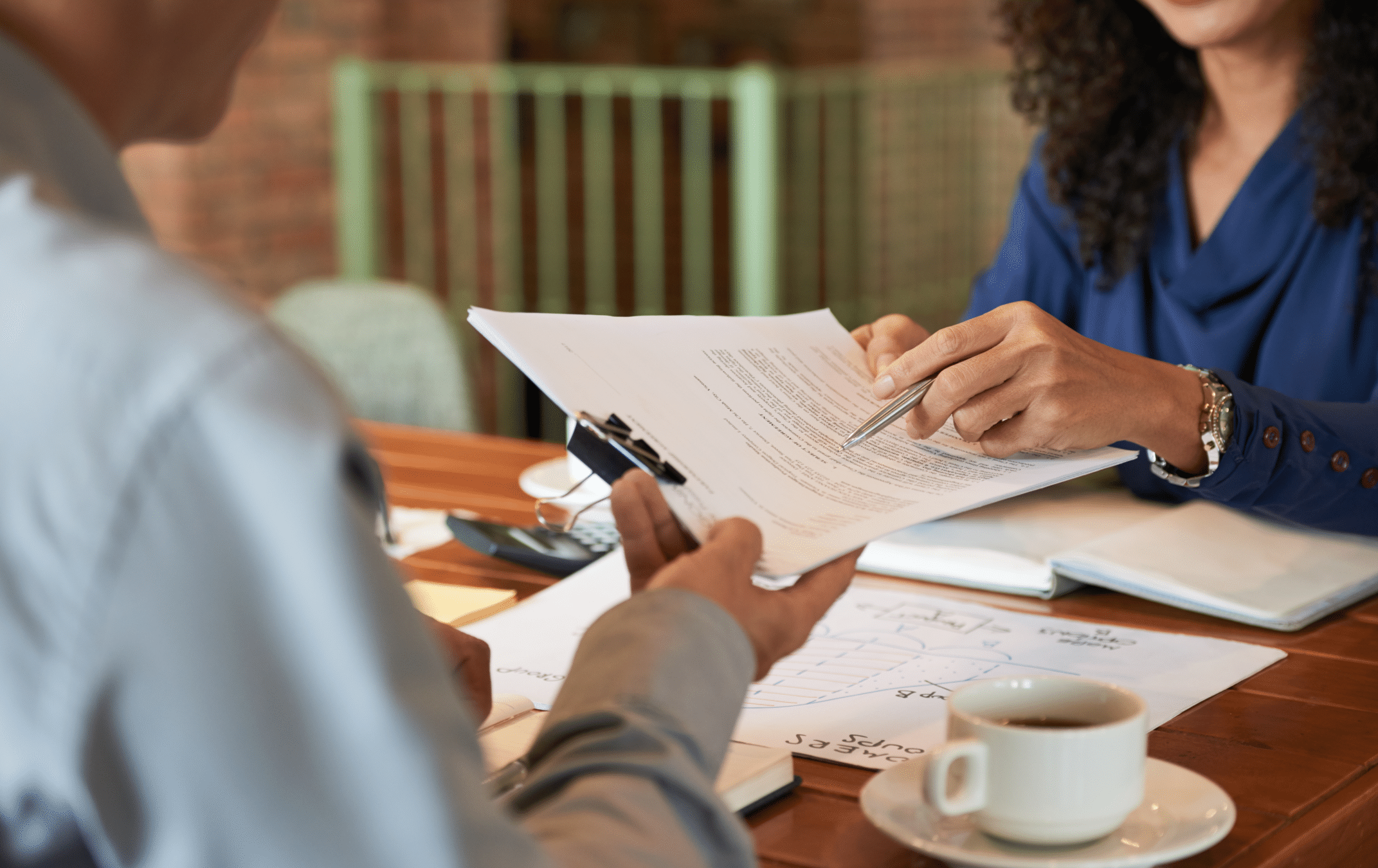 Um homem e uma mulher sentados em uma mesa assinando papéis