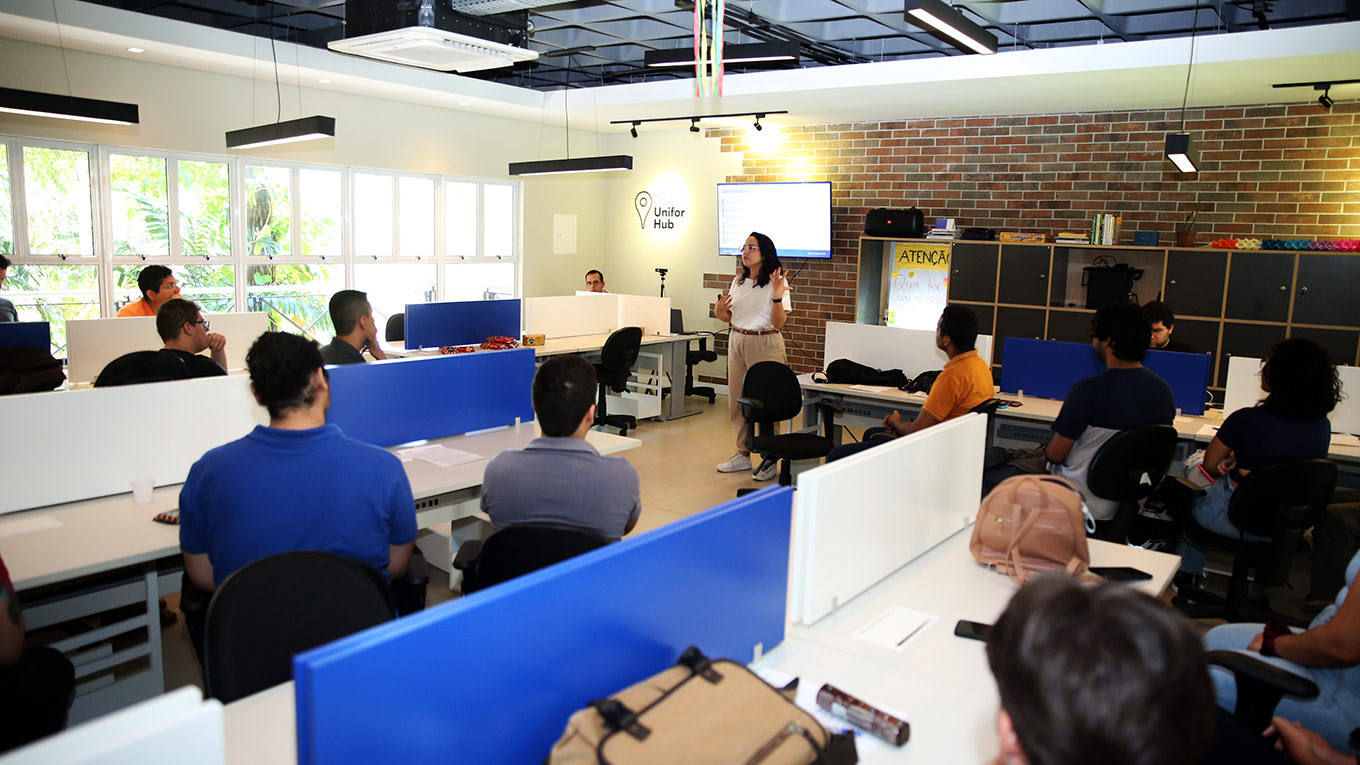 Sala da EDETEC com pessoas de ambos os sexos usando computadores e notebooks.