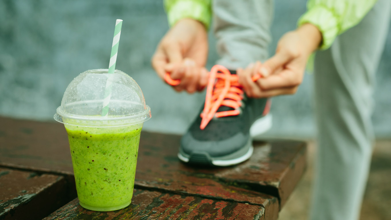 Pessoa amarra o cadarço do sapato antes de tomar uma vitamina.